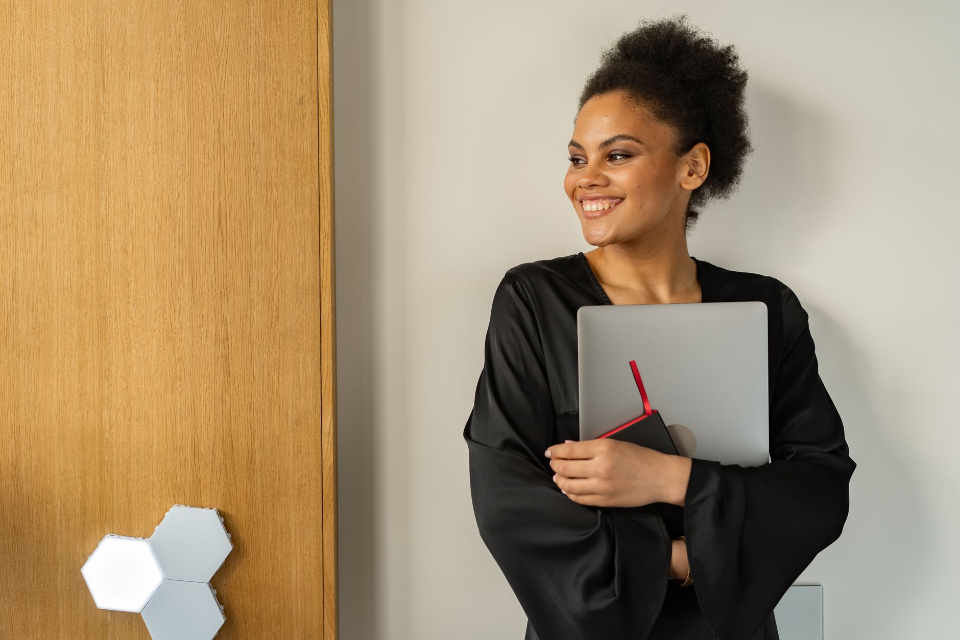 Smiling woman with afro holding a laptop indoors, exuding confidence and positivity